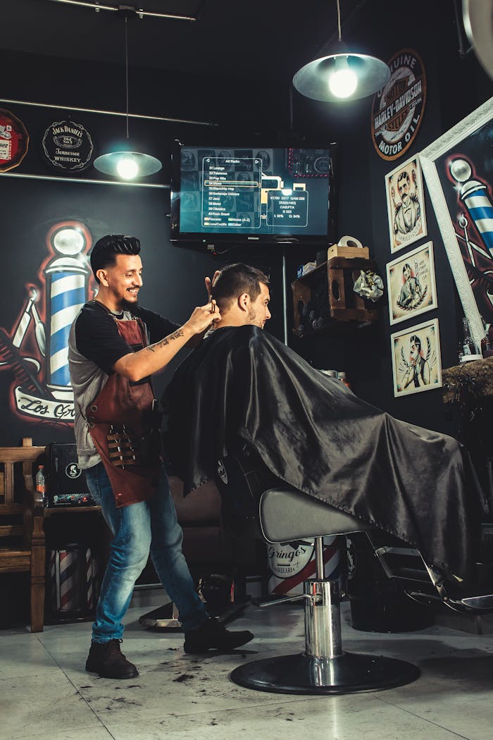A barber skillfully cutting a mans hair in a trendy, well-decorated barbershop.