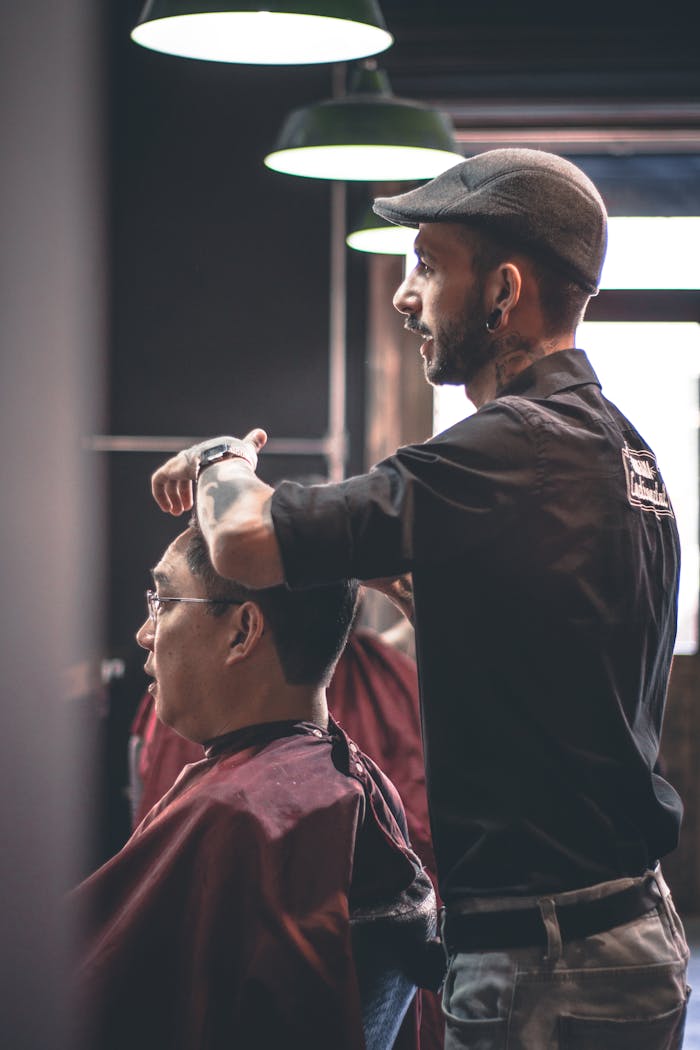 services-02 Barber skillfully trims customers hair in a modern salon, capturing hairstyle expertise.
